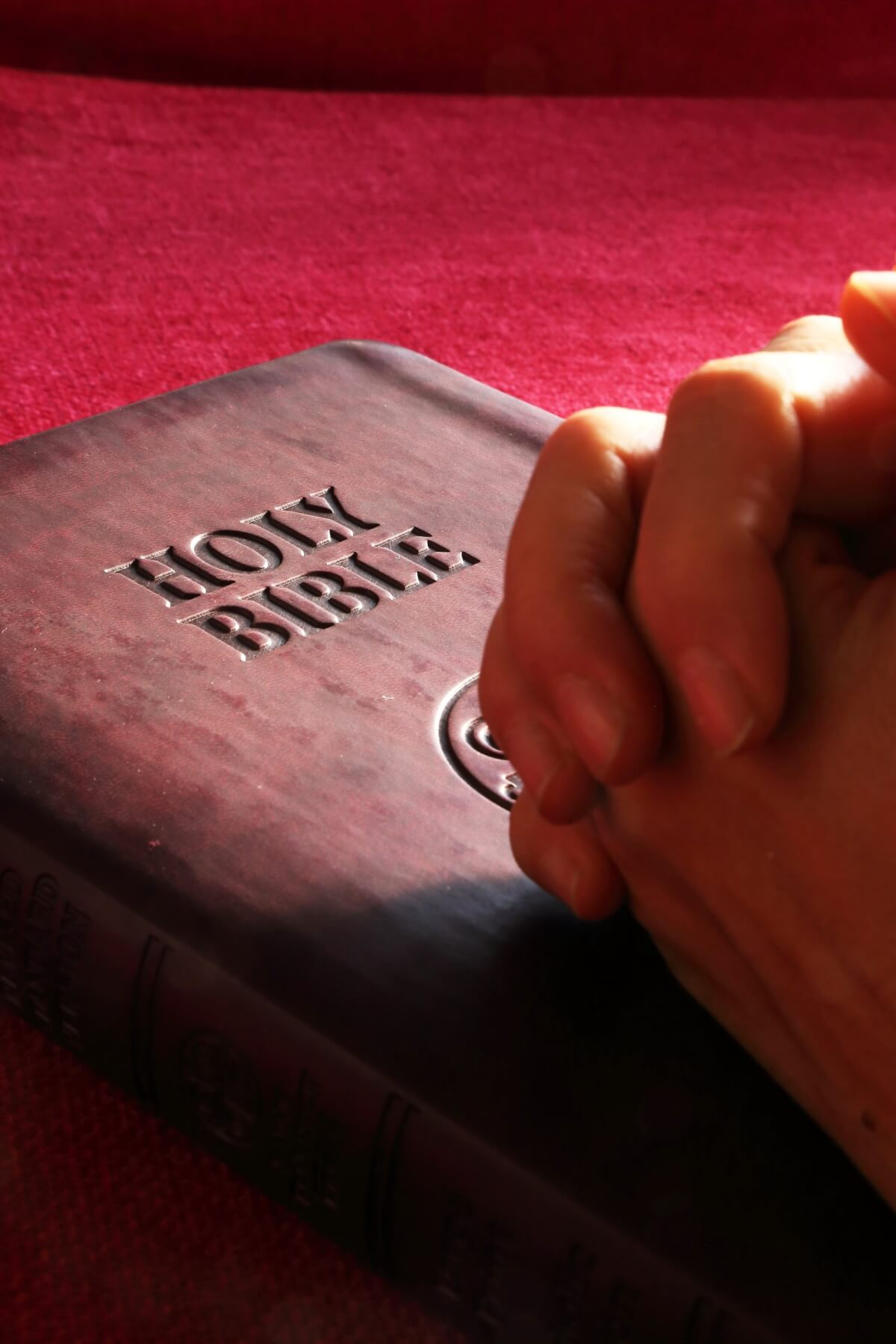 Hands on a bible praying