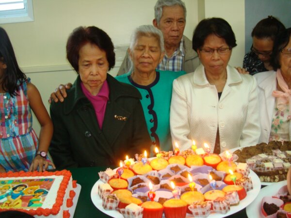 Church Elders praying before candle-lit muffins