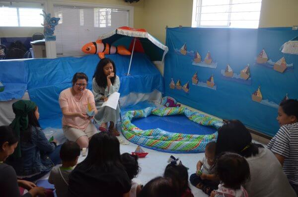 Woman instructing kids on how to build a paper boat