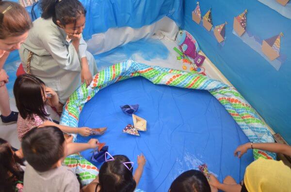 Children trying out their paper boats in a pool of water