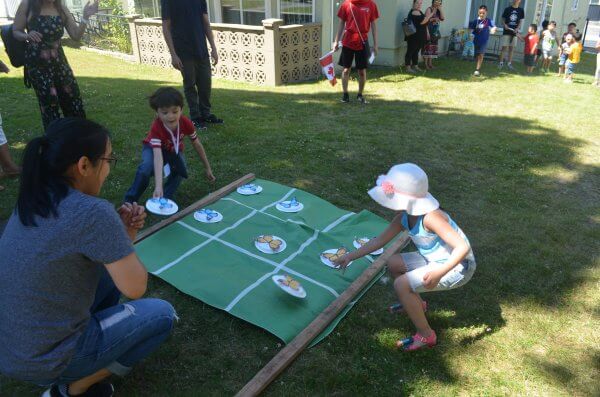 Two kids place their plate on a tic-tac-board