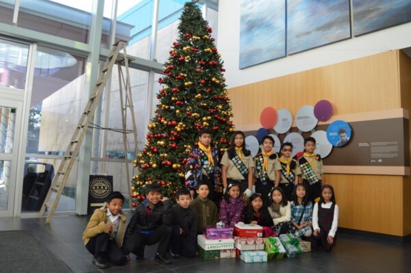 Pathfinders posing in front of a Christmas tree with gifts